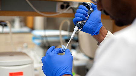 Doctor wearing rubber gloves holds syringe and vial in hands