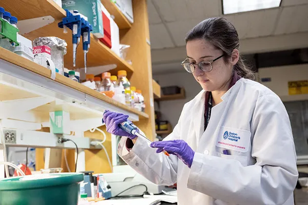Lab technician looks at vials and other lab instruments