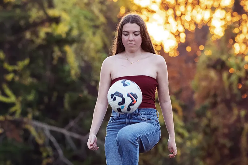 Teenage girl bounces soccer ball off knee