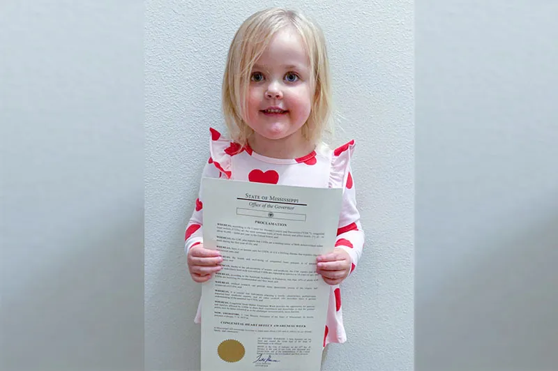 Girl holds sheet of paper while standing up to pose for picture