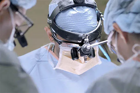 Doctor in scrubs wears magnifying glasses on head in operating room